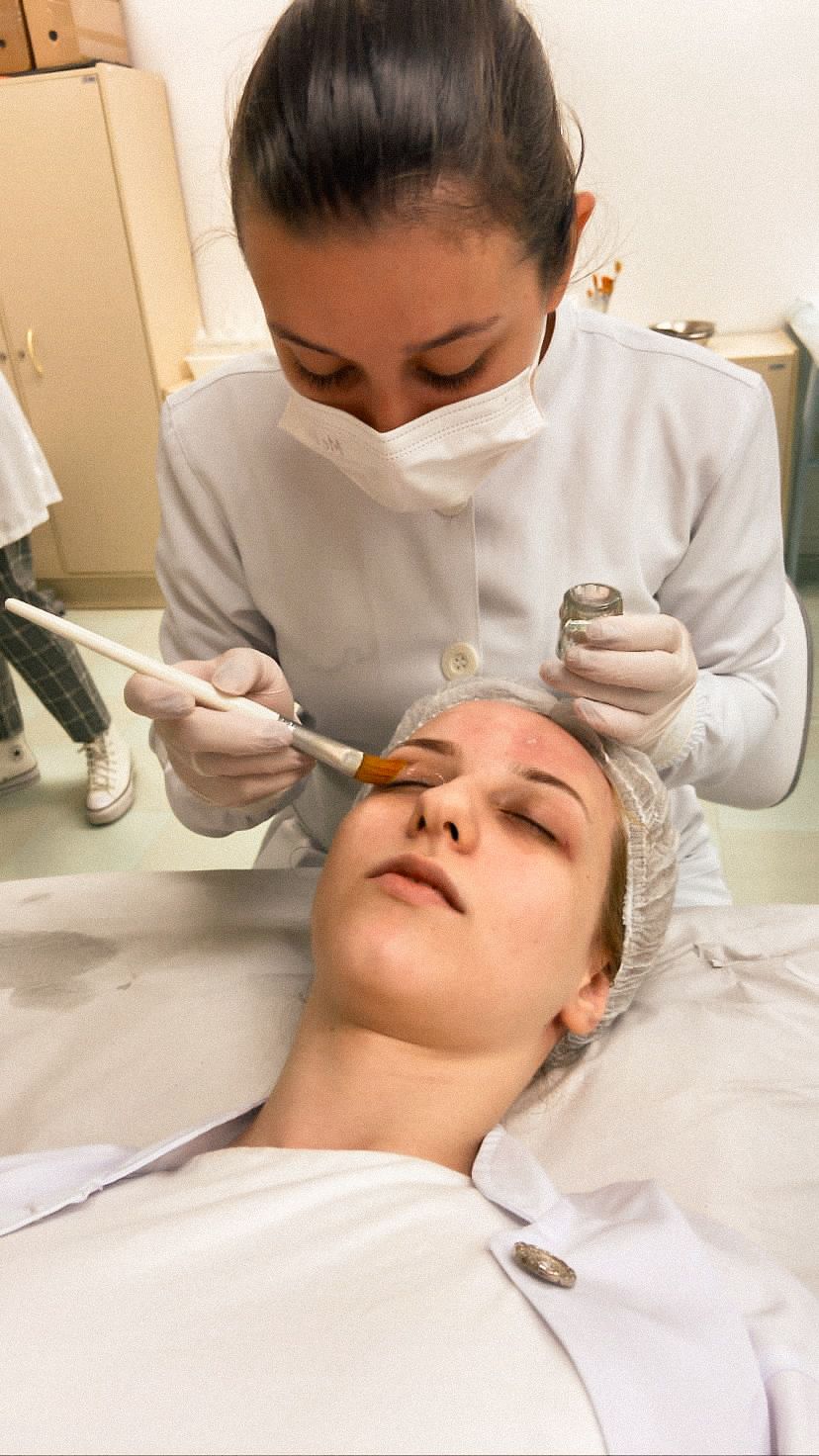 Marciele aplicando produto facial com pincel durante procedimento estético